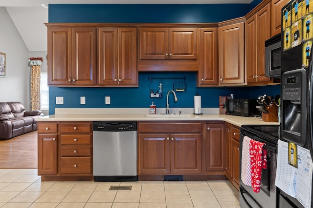 kitchen with sink, vaulted ceiling, light tile patterned floors, and stainless steel appliances