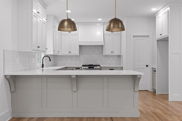 kitchen with pendant lighting, sink, custom exhaust hood, and white cabinets