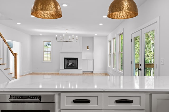 kitchen featuring light stone counters, stainless steel oven, plenty of natural light, and decorative light fixtures