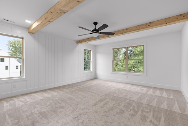 carpeted empty room with beamed ceiling, ceiling fan, and a wealth of natural light