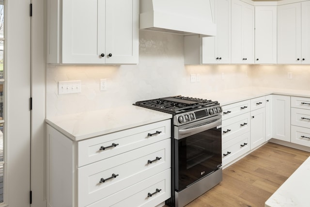 kitchen featuring white cabinetry, stainless steel range with gas cooktop, light hardwood / wood-style flooring, and premium range hood