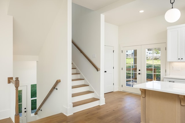 interior space with pendant lighting, french doors, white cabinets, and light wood-type flooring