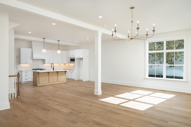 kitchen with white cabinets, light hardwood / wood-style flooring, hanging light fixtures, and a spacious island