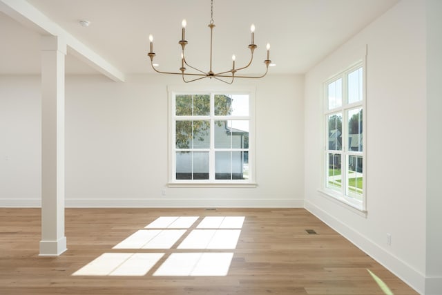 unfurnished dining area with light hardwood / wood-style flooring, a wealth of natural light, and a chandelier