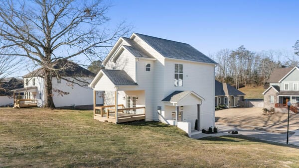 back of property featuring a wooden deck and a yard