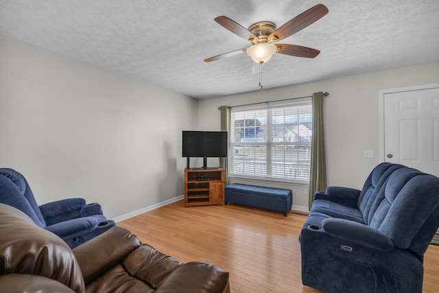 living room with ceiling fan, light hardwood / wood-style floors, and a textured ceiling