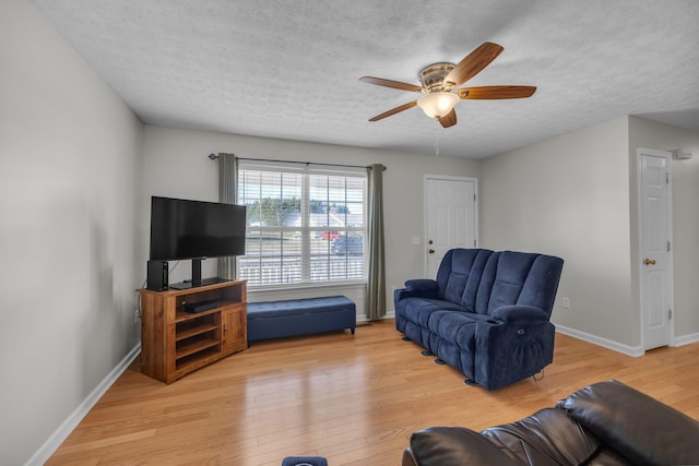 living room featuring light hardwood / wood-style floors, a textured ceiling, and ceiling fan