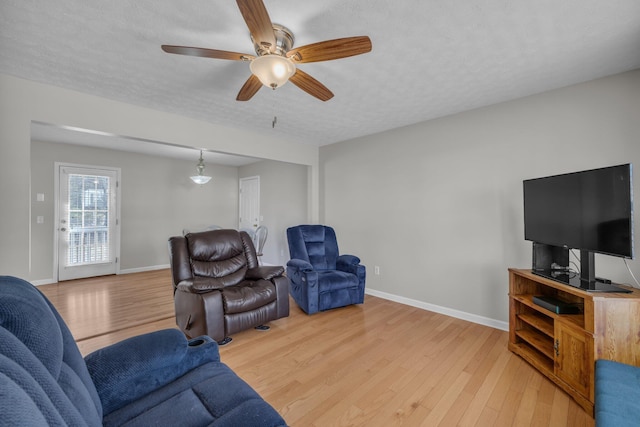 living room featuring light wood-type flooring, a textured ceiling, and ceiling fan