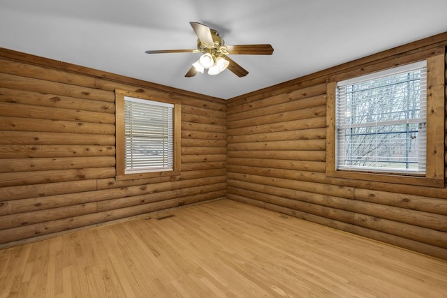 spare room with ceiling fan, rustic walls, light hardwood / wood-style flooring, and a wealth of natural light