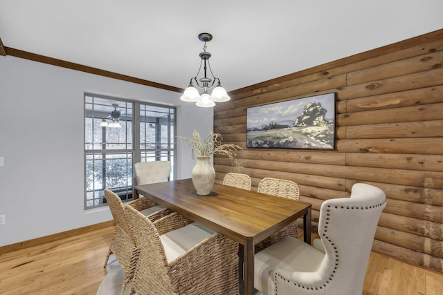 dining room featuring rustic walls, ornamental molding, a notable chandelier, and light hardwood / wood-style flooring