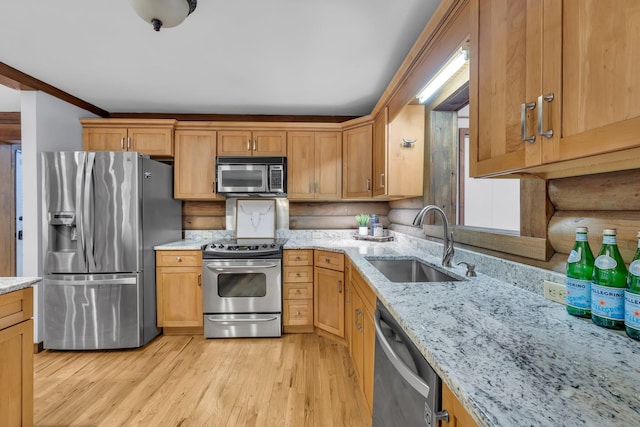 kitchen featuring rustic walls, sink, light wood-type flooring, stainless steel appliances, and light stone countertops