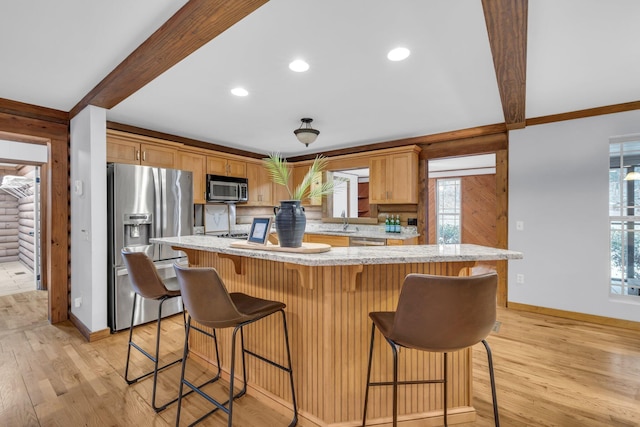 kitchen with beamed ceiling, appliances with stainless steel finishes, a wealth of natural light, and a kitchen bar