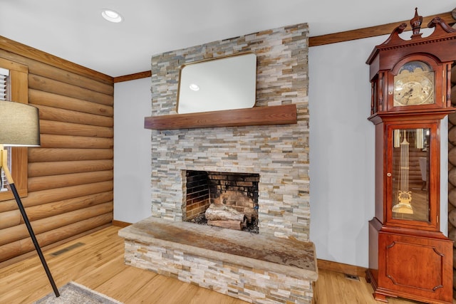 living room with log walls, a fireplace, and light wood-type flooring