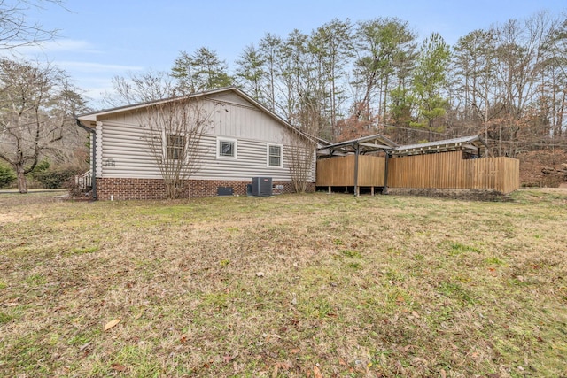 view of side of home with a wooden deck, a yard, and central AC