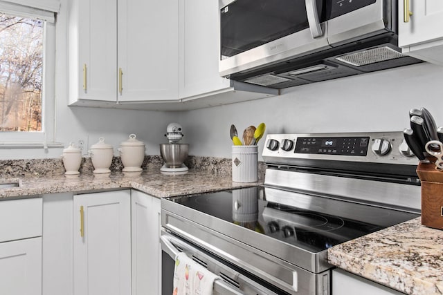 kitchen with white cabinetry, light stone counters, and appliances with stainless steel finishes