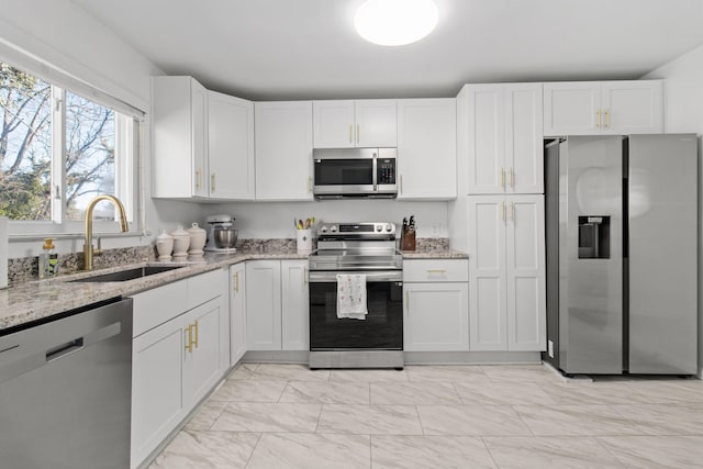 kitchen featuring stainless steel appliances, sink, white cabinets, and light stone counters