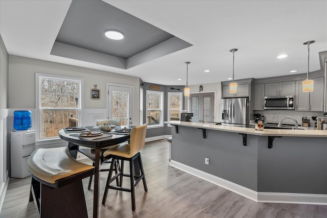 dining room featuring hardwood / wood-style flooring, sink, and a raised ceiling