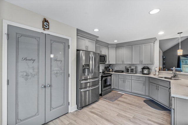 kitchen featuring gray cabinetry, decorative backsplash, sink, pendant lighting, and stainless steel appliances