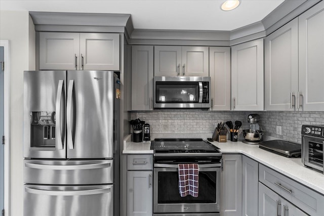 kitchen featuring backsplash, appliances with stainless steel finishes, and gray cabinetry