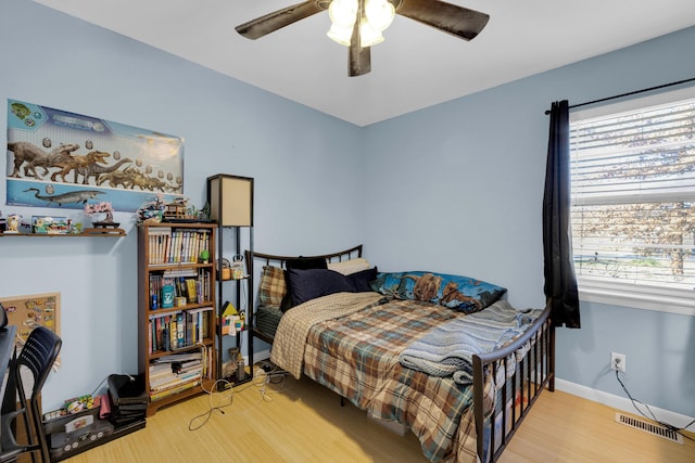 bedroom with ceiling fan, wood-type flooring, and multiple windows