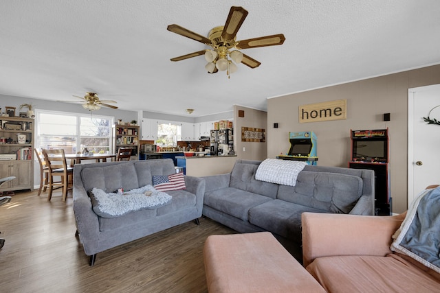 living room featuring dark wood-type flooring, ceiling fan, and a textured ceiling