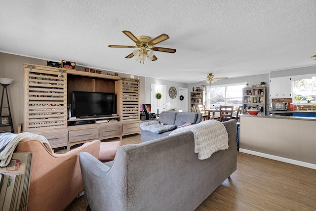 living room with a textured ceiling, wood-type flooring, and ceiling fan