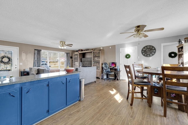 kitchen featuring ceiling fan, blue cabinets, light hardwood / wood-style flooring, and a textured ceiling