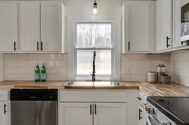 kitchen featuring butcher block countertops, sink, white cabinetry, stainless steel appliances, and decorative backsplash