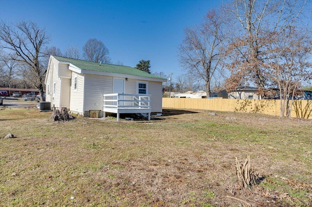 rear view of property featuring central AC unit and a lawn