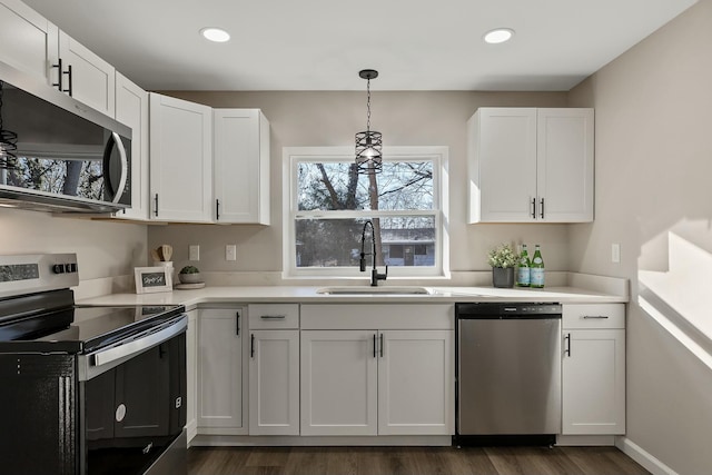 kitchen featuring stainless steel appliances, decorative light fixtures, sink, and white cabinets