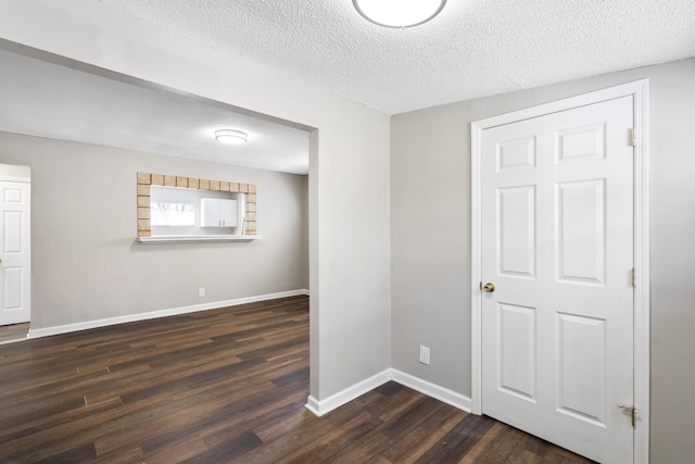 empty room with dark wood-type flooring and a textured ceiling