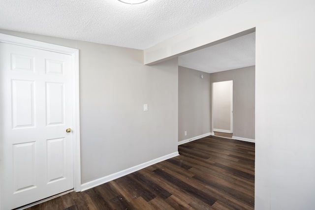 unfurnished room with dark hardwood / wood-style flooring and a textured ceiling