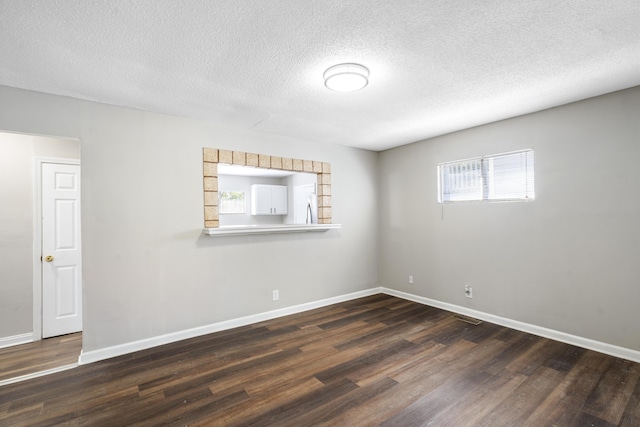 unfurnished room with a textured ceiling and dark hardwood / wood-style flooring