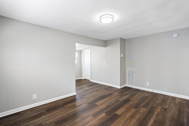 unfurnished room featuring a textured ceiling and dark hardwood / wood-style flooring