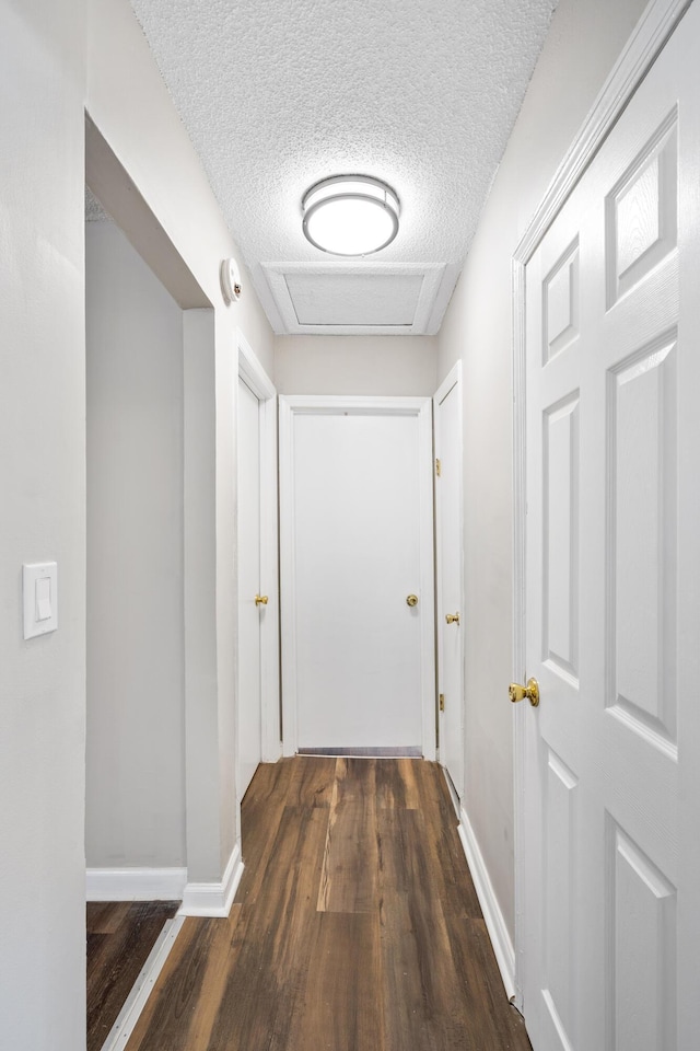 hall with a textured ceiling and dark hardwood / wood-style floors