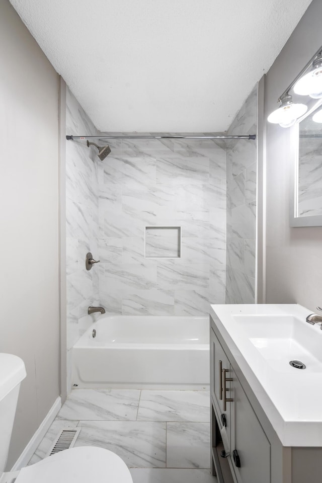 full bathroom featuring a textured ceiling, toilet, vanity, and tiled shower / bath combo