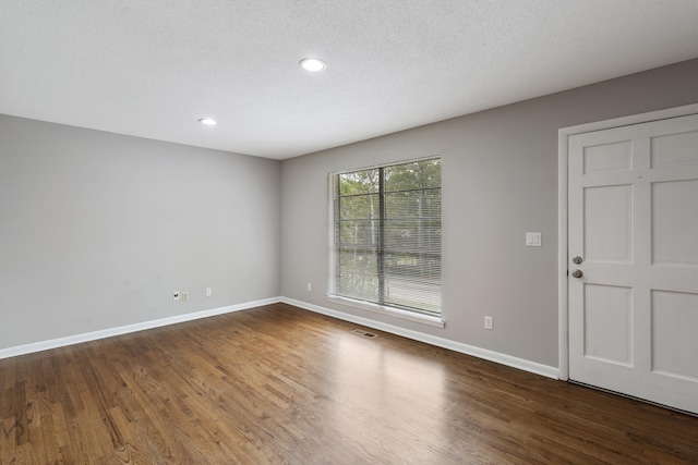 unfurnished room featuring dark hardwood / wood-style floors and a textured ceiling