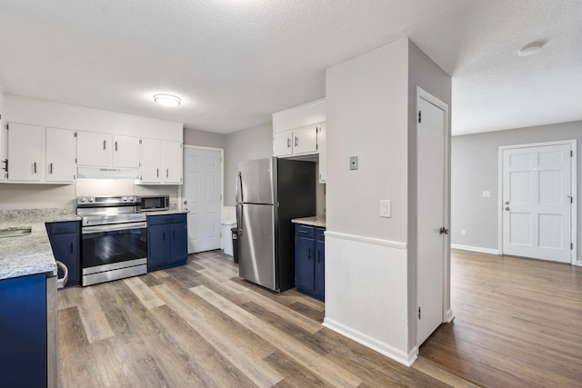 kitchen with light hardwood / wood-style floors, white cabinetry, appliances with stainless steel finishes, and a textured ceiling