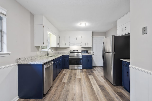 kitchen featuring sink, white cabinets, blue cabinets, and appliances with stainless steel finishes