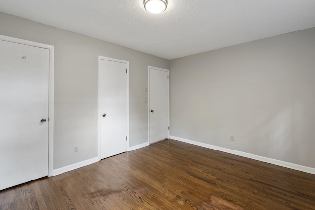 unfurnished bedroom featuring a textured ceiling and dark hardwood / wood-style flooring