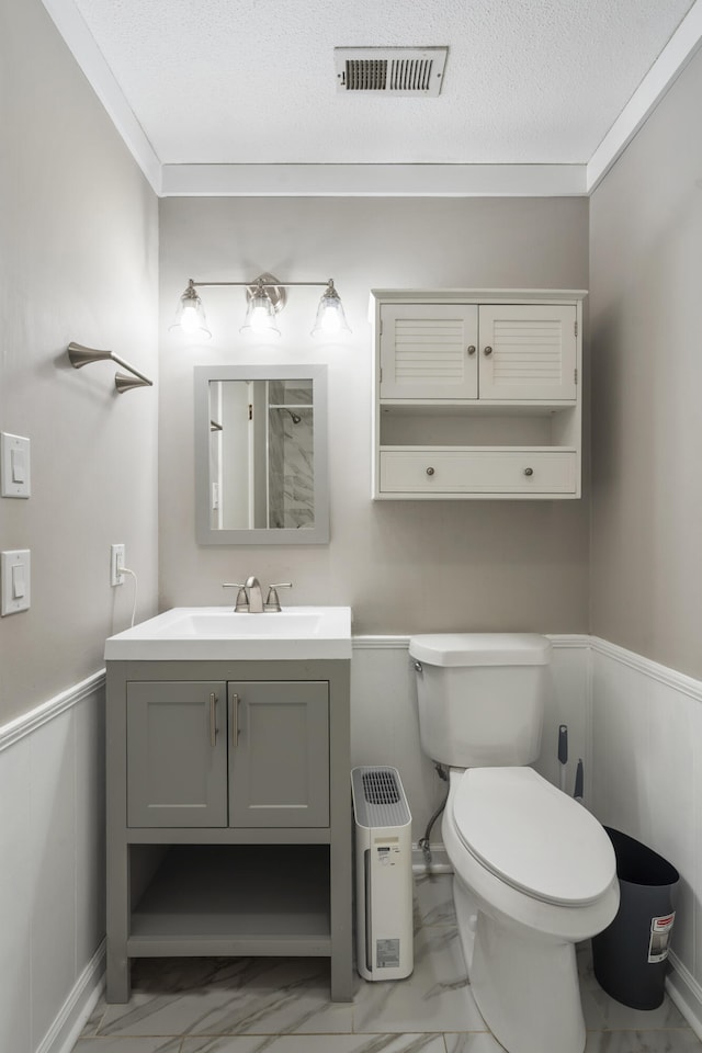 bathroom with vanity, toilet, ornamental molding, and a textured ceiling