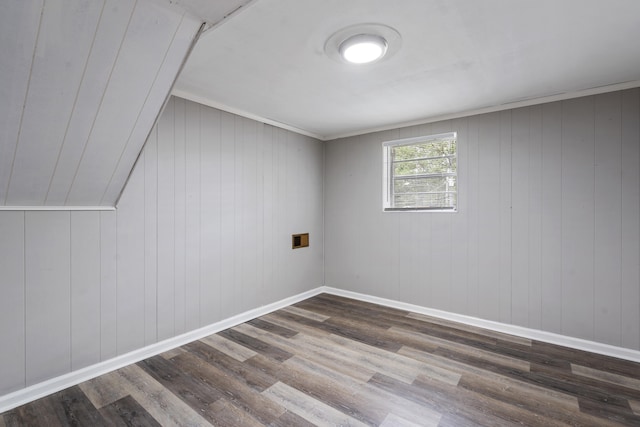 additional living space featuring vaulted ceiling, wooden walls, and dark wood-type flooring