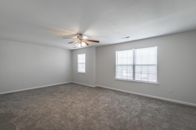 spare room featuring dark colored carpet, a textured ceiling, and ceiling fan