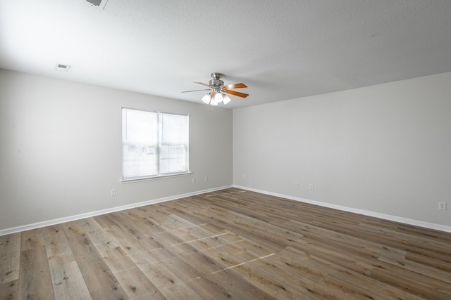 empty room featuring a textured ceiling, ceiling fan, and light wood-type flooring