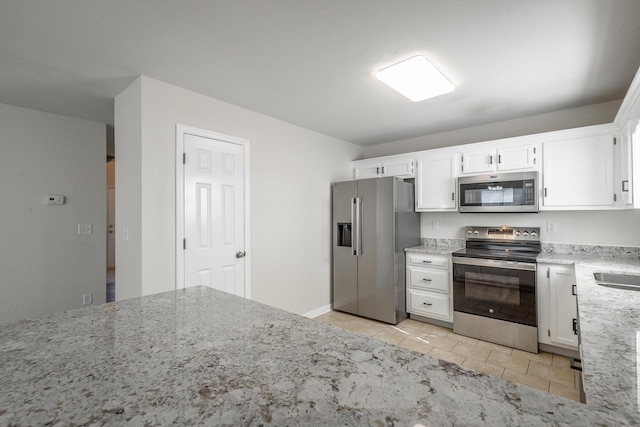 kitchen featuring light tile patterned floors, sink, appliances with stainless steel finishes, white cabinetry, and light stone countertops