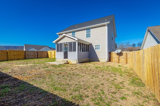 rear view of property featuring a sunroom and a lawn