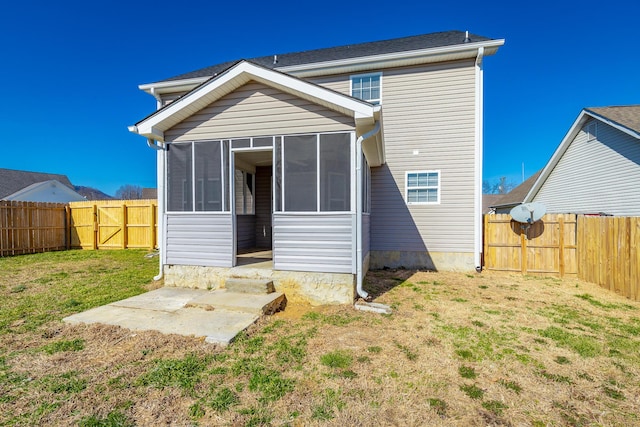 rear view of house featuring a sunroom and a lawn