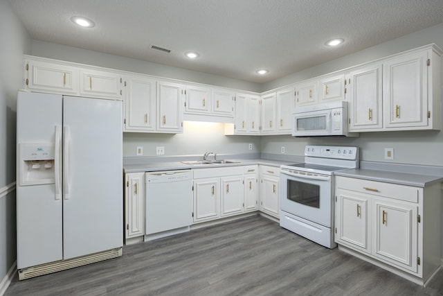 kitchen with sink, white appliances, dark wood-type flooring, a textured ceiling, and white cabinets