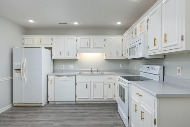 kitchen featuring sink, white appliances, white cabinetry, hardwood / wood-style floors, and a textured ceiling