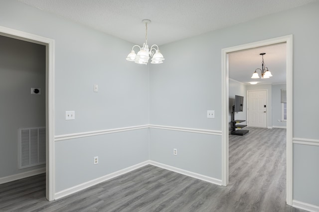 spare room with an inviting chandelier, hardwood / wood-style flooring, and a textured ceiling